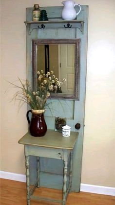 a vase with flowers sitting on top of a table next to a mirror and shelf