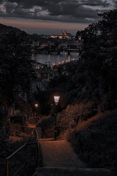 stairs leading up to the top of a hill at night with lights on and over water in background