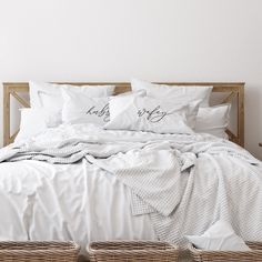 a bed with white sheets and two baskets under it