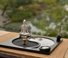 a small statue sitting on top of a wooden table next to a candle and some rocks