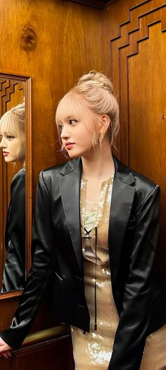 a woman standing in front of a mirror next to a mannequin's head