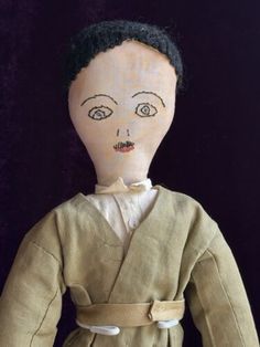 an old doll with black hair wearing a brown outfit