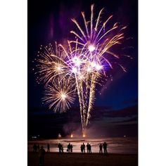 people are standing on the beach watching fireworks