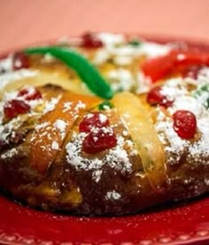 a red plate topped with a pastry covered in powdered sugar and toppings on top of it