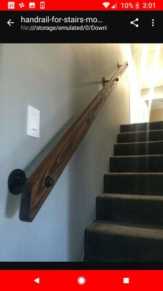 a wooden stair rail on the side of a wall next to a light switch and stairs