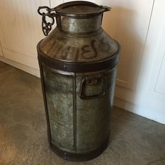 an old metal urn sitting on the floor in front of a white paneled wall