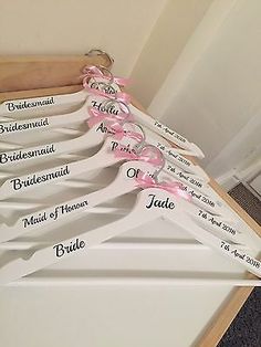 six bridesmaid hangers with pink bows and names on them in a closet