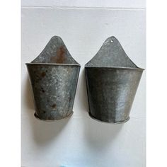 two metal buckets are hanging on the wall