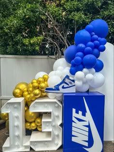 balloons and nike shoes are on display in front of a wall with the letter e