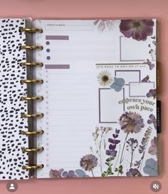 an open planner book with purple flowers and polka dots on the cover, next to a pink background