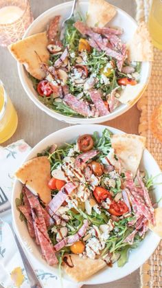 two white bowls filled with salad on top of a table