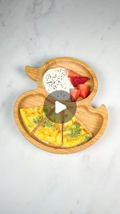 a wooden plate topped with pizza and fruit on top of a white countertop next to a knife