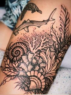 a woman's thigh with an artistic tattoo design on her leg and dolphin in the background