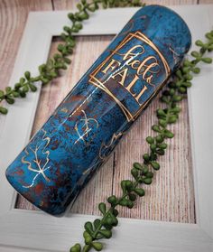 an old blue tube with writing on it sitting next to some green plants and leaves