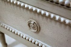 a close up view of a white dresser with beading on the drawers and handles