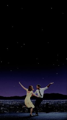 a man and woman dancing in front of the night sky