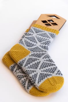 a pair of yellow and gray socks on a white surface with a wooden tag attached to the sock