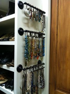 there are many bracelets hanging on the wall next to shoes and purses in this closet