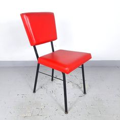 a red chair sitting on top of a tiled floor