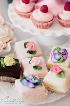 there are many small cakes and cupcakes on the table with pink flowers in them