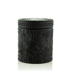 a black metal container with flowers and leaves on the inside, sitting on a white surface