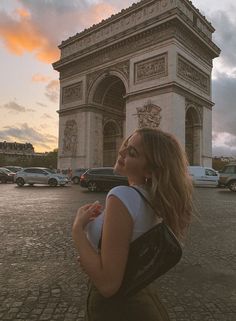 a woman standing in front of the arc de trio triumph