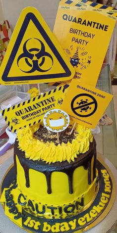 a birthday cake decorated with yellow and black icing, has a sign that says quarantine birthday party