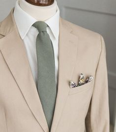 a man in a suit with a green tie and flower brooch on his lapel