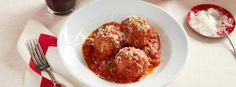 meatballs covered in marinara sauce and parmesan cheese on a white plate