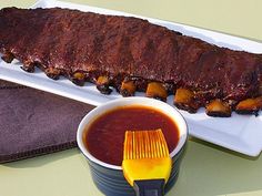 barbecue ribs and sauce on a plate next to a napkin with a brush in it