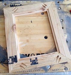 a wooden frame sitting on top of a table next to a ruler and screwdriver