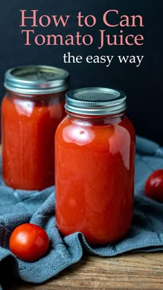 two mason jars filled with tomato juice on top of a wooden table next to a blue towel