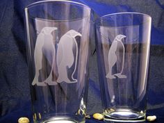 two glasses with penguins on them sitting next to each other