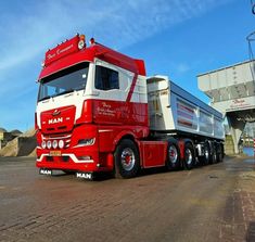 a red and white semi truck parked in front of a building