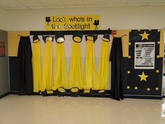 some yellow and black curtains are hanging in front of a sign that says look who's in the spotlight