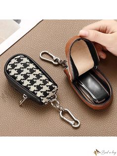 a hand holding a black and white purse with a keychain attached to it