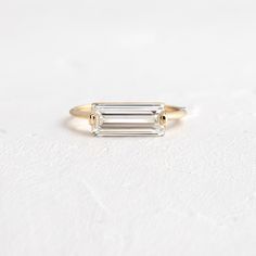 a gold ring with an emerald cut diamond on the front, and two smaller baguettes in the back