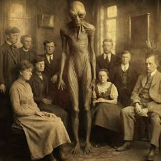 an alien standing in front of a group of men and women, all looking at the camera