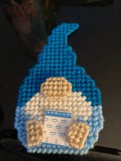 a blue and white knitted teddy bear sitting on top of a laptop computer