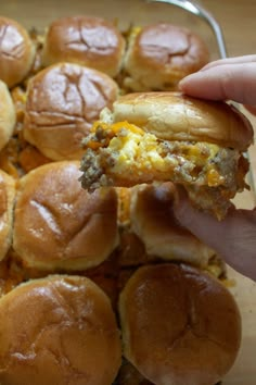 a person is holding up a sandwich in front of some buns