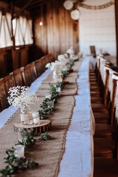 a long table with candles and greenery on it in a room filled with wood paneled walls