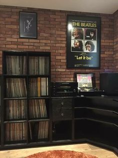 an old record player is sitting in front of a brick wall with records on it