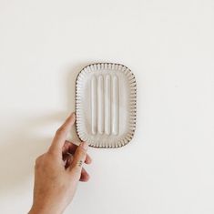 a person is holding an object in front of a white wall and pointing at it