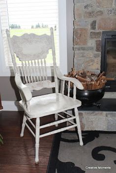 a white rocking chair sitting in front of a fireplace