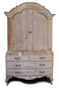 an old white dresser sitting next to a wall