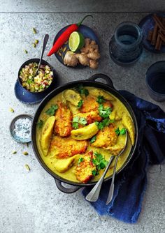 a pan filled with chicken curry next to other dishes