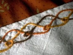 an orange and yellow piece of cloth on top of a white tablecloth with gold thread