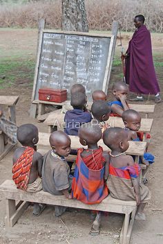 a group of children sitting on top of a wooden bench in front of a chalkboard