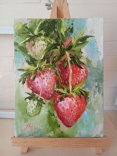 a painting of strawberries hanging on a easel