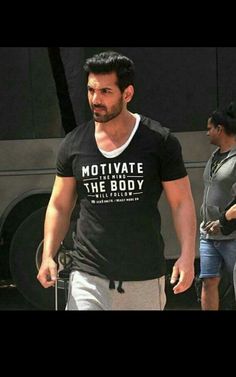 a man walking down the street wearing a t - shirt that says motivitate the body